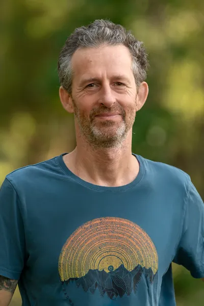 Rémi Perrot, souriant, en extérieur devant un feuillage